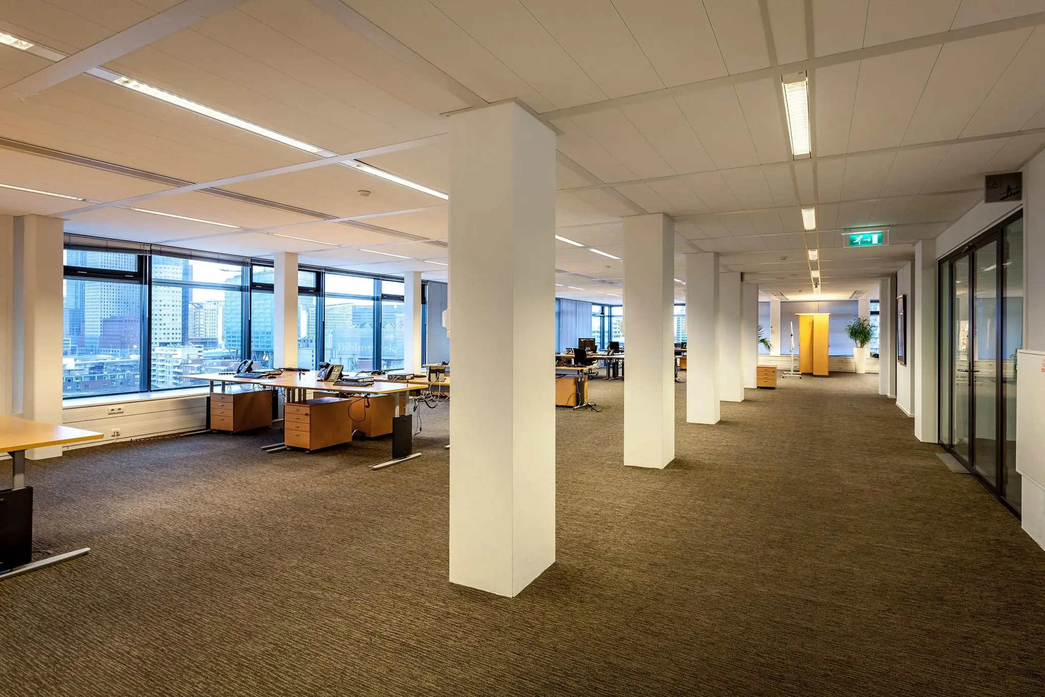 Moderne open kantoorruimte aan de Prinses Beatrixlaan met bureaus, grote ramen en uitzicht op de stad.